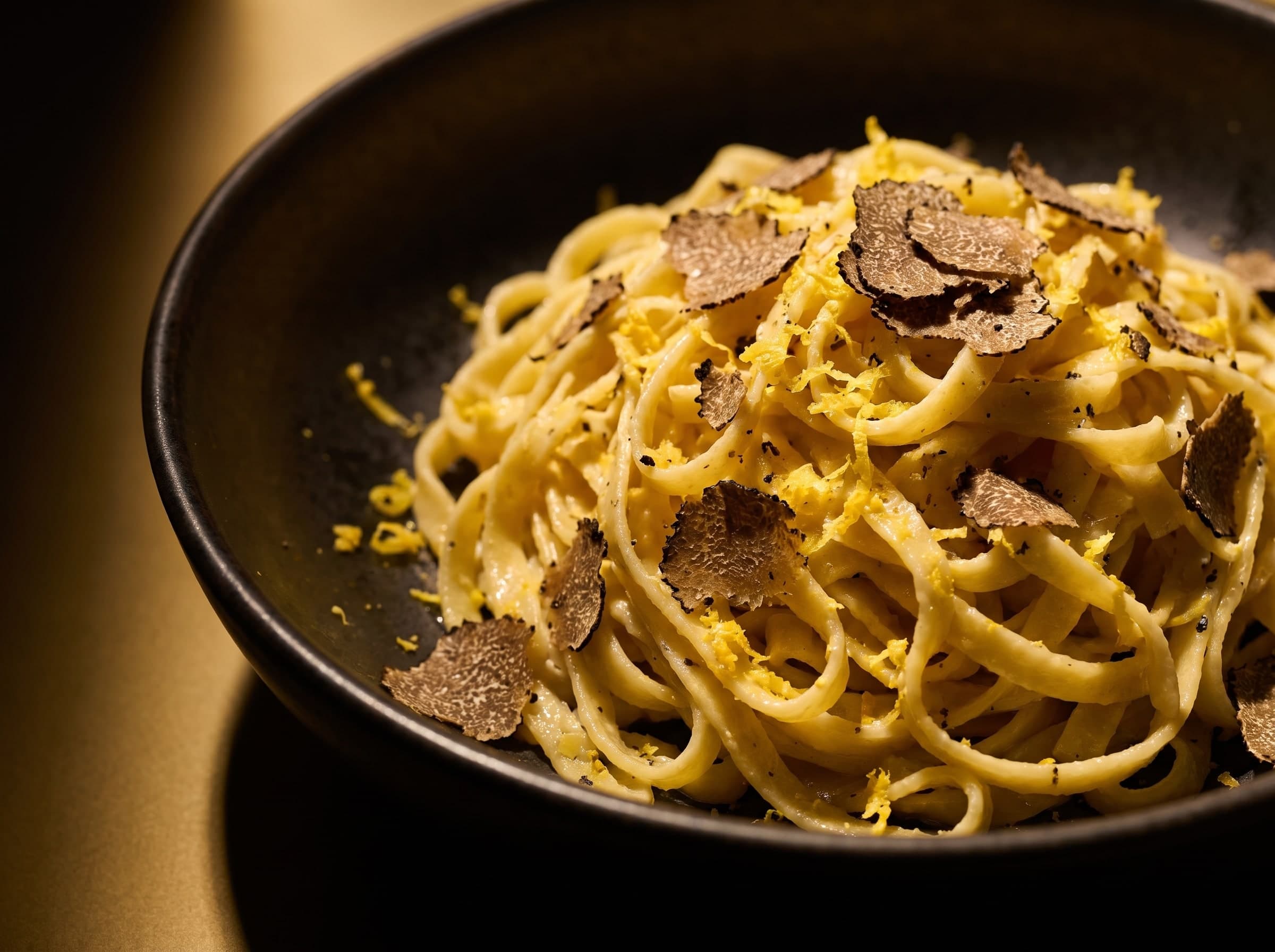 Tagliolini mit Zitronenzeste und gehobeltem schwarzem Trüffel in dunkler Schale